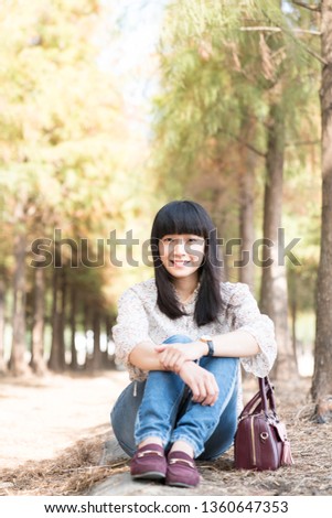 Asian girl in the woods. There are many pines and plants in the woods.