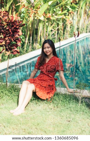 Pretty Asian woman is relaxing in the pool villa.
