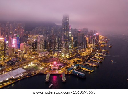 Aerial view of Hong Kong Downtown and Victoria Harbour with rain storm and fog. Financial district, business centers in smart city and technology concept. skyscraper and high-rise buildings at night.