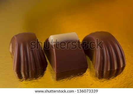 Photograph of three different chocolates on a yellow background.