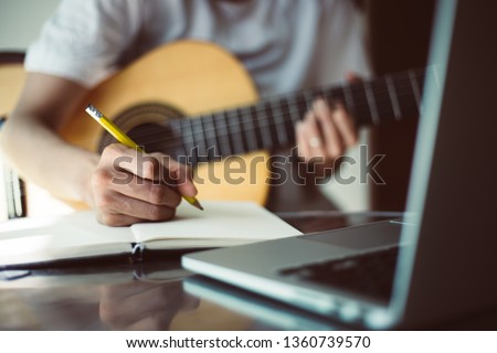songwriter thinking and writing notes,lyrics in book at studio.man playing live acoustic guitar.concept for musician creative.artist composer in work process.people relaxing time with instrument Royalty-Free Stock Photo #1360739570