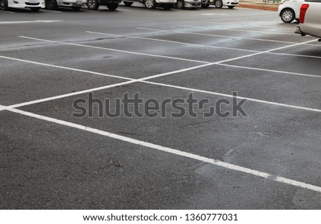 Image of empty parking spaces on asphalt ground of parking area after raining in twilight evening.