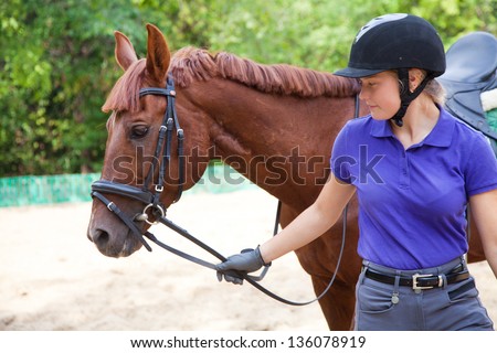 young woman rider and horse in training place Royalty-Free Stock Photo #136078919