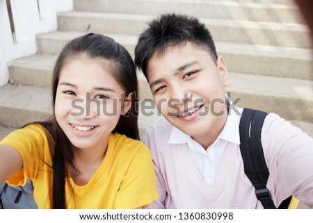 Couple Young asian teenager boy and girl sitting on stair and taking their photo selfie by smartphone
