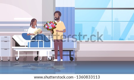 husband holding flowers bouquet for his wife with newborn baby loving father visiting new born child happy african american family parenthood concept hospital ward interior horizontal