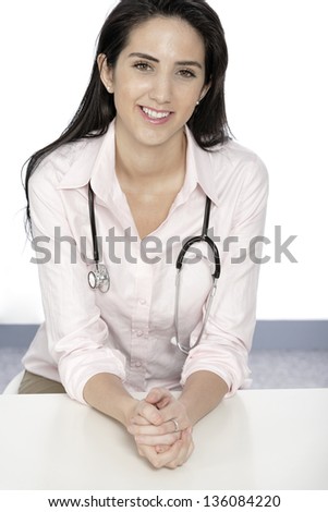 Beautiful young doctor sat smiling at her work desk