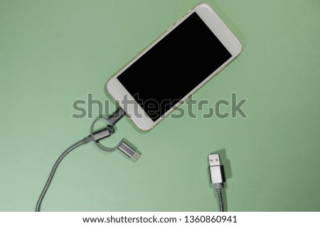 Usb cable with three different point ends charging a mobile phone. Technology connect close up. Charge diffrent types of devices with one cord.