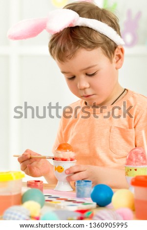 little child boy with Easter bunny ears painting Easter eggs at home. adorable child prepare for easter. Happy easter