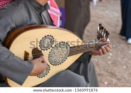 Arabic musician from Saudi Arabia plays on traditional instrument from Middle East called Oud or Ud. Royalty-Free Stock Photo #1360991876