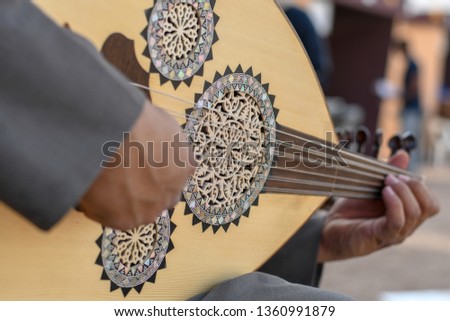 Arabic musician from Saudi Arabia plays on traditional instrument from Middle East called Oud or Ud. Royalty-Free Stock Photo #1360991879