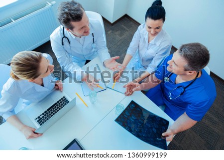 Professional discussion. Attentive blonde holding her laptop and turning head while sitting near her colleagues
