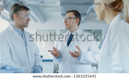 Team of Research Scientists Have Meeting, They Have Discussion While Standing in the Middle of Laboratory. People in Innovative Modern Lab Doing Genetics and Pharmaceutical Studies.