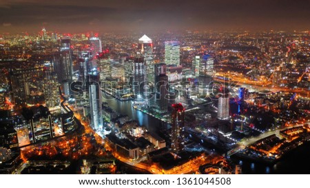 Aerial drone night shot from iconic Canary Wharf illuminated skyscrapers business and financial area, Docklands, Isle of Dogs, London, United Kingdom