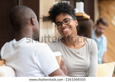Happy young african american woman smiling enjoy fun conversation with man friend boyfriend, mixed race teen girl in love talk laughing flirting at meeting, black couple on first date outdoor concept Royalty-Free Stock Photo #1361068505