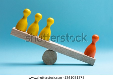 Close-up Of Red And Yellow Pawns Figures Balancing On Wooden Seesaw Over Blue Surface Royalty-Free Stock Photo #1361081375