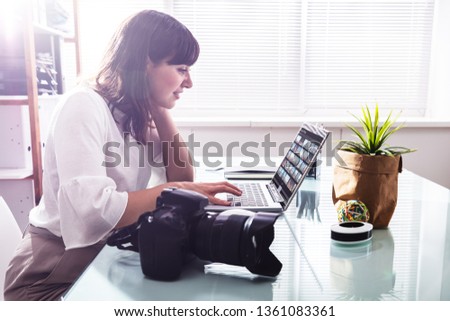 Editor Retouching Photos On Laptop With DSLR Camera On Desk