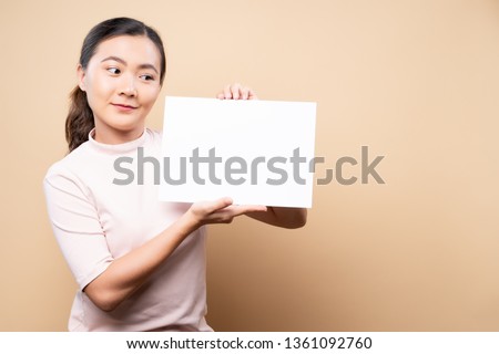 Woman showing paper copy space isolated over beige brown background