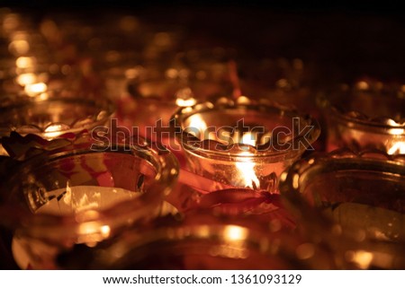 Close-up of group cluster collection of votive candles burning in small glass jars