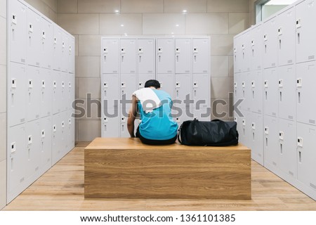 man with towel sitting on wooden bench in gym. Royalty-Free Stock Photo #1361101385