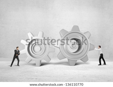 two businessman pushing gears on concrete background