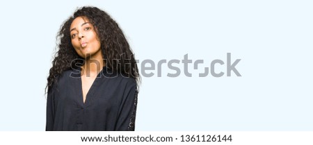Young beautiful girl with curly hair wearing elegant dress making fish face with lips, crazy and comical gesture. Funny expression.