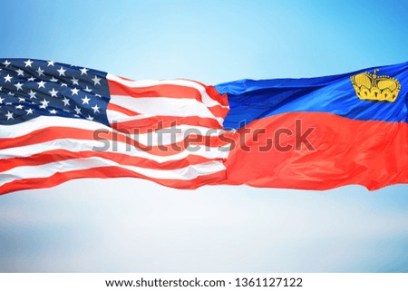 Flags of the USA and Liechtenstein against the background of the blue sky