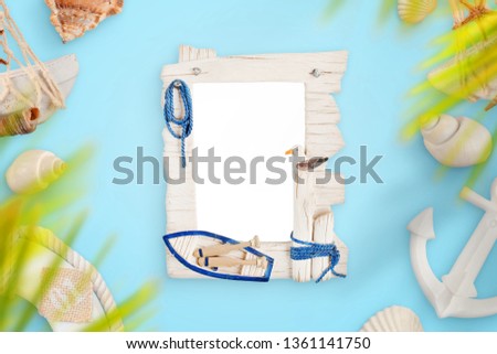 Photo frame on blue desk surrounded with smmer, travel, sea decorations.