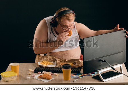 fat man watching online football translation. close up photo. isolated black background.hockey fan. entertainment