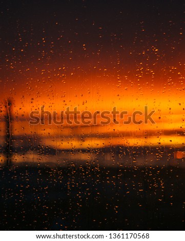 Glass in the drops of rain at sunset. The windows of a residential apartment. Orange sky