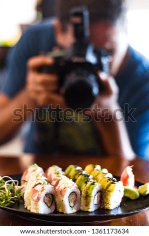 People, leisure, food, food and technology - close up of man with camera taking a picture of sushi in the restaurant.