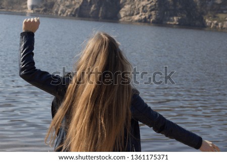 Beautiful girl with long blond hair is dancing near the water