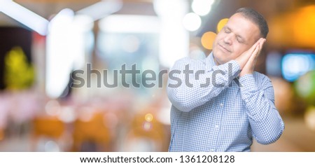 Middle age arab business man over isolated background sleeping tired dreaming and posing with hands together while smiling with closed eyes.
