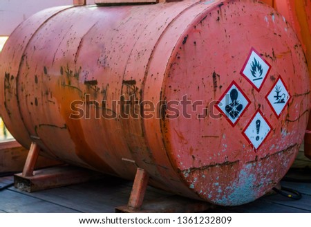 old rusty silo tank containing hazardous substances, warning labels on the side, storage of dangerous liquids