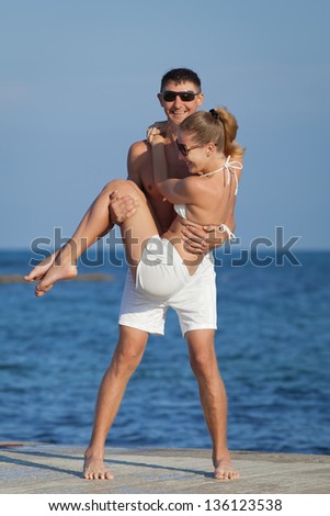 Attractive couple at the sea. Guy holding on hands his girl at seashore in day time
