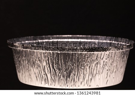 Closeup view of new empty food container made of aluminium foil isolated on black background. Container can be used in microwaves, ovens, fridges. Horizontal color photography.