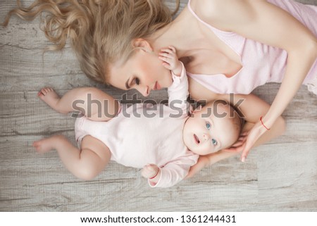 Young mother with her little cute baby daughter. Little baby girl and her mom. Mama with her child indoor.