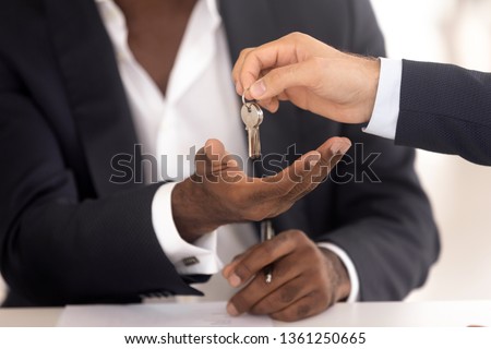 Male realtor real estate agent hand give keys to african american new home owner make sale purchase deal, black customer renter buyer tenant buy house, mortgage investment, property ownership concept Royalty-Free Stock Photo #1361250665