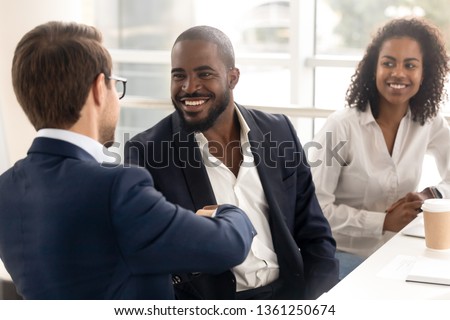 Happy african businessman handshake reliable male partner at team meeting, smiling diverse workers shake hand as respect trust concept, making deal business agreement with client at group negotiation Royalty-Free Stock Photo #1361250674