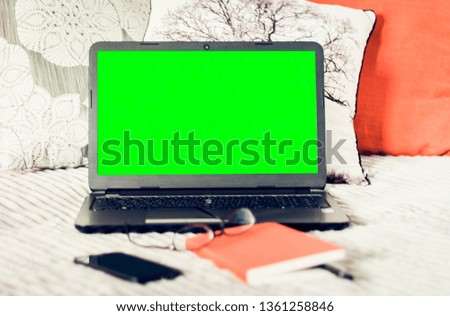 Green screen laptop, notebook, smartphone, glasses and pen on bad, education concept background.