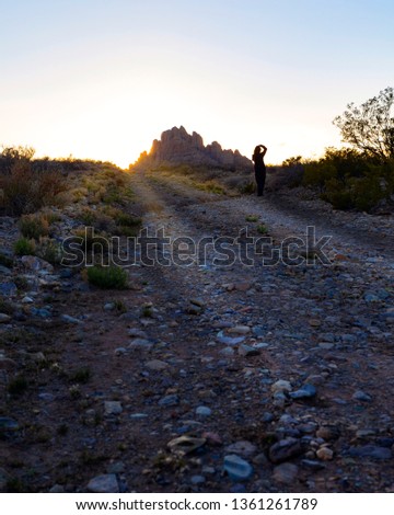 A person taking a picture of a lone desert mountain at sunset. 