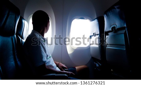 Young passenger looking out through window of the airplane, Selective focus. Royalty-Free Stock Photo #1361276321