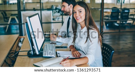 Portrait of successful female coworker looking at camera during break of searching information about finance news in world via modern computer with blank screen for your internet advertising