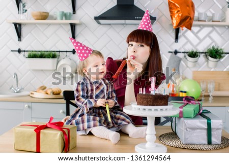 Baby and mother blowing into party horn