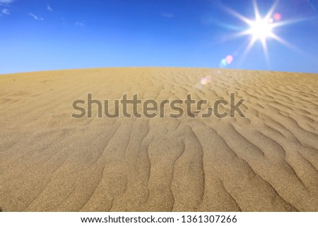 Summer background of sand on beach and blue sky with sun. Free space for your decoration. 