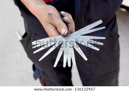 Mechanic holding  tappet feeler gauge set in dirty hands Royalty-Free Stock Photo #136132967