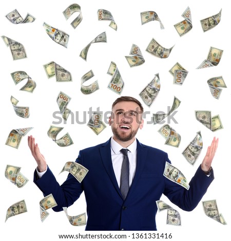 Happy young businessman under rain of money on white background