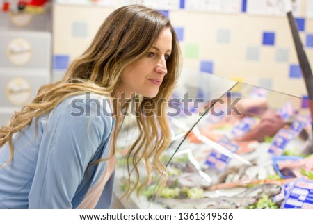 Women choosing a dairy products at supermarket. Reading product information
