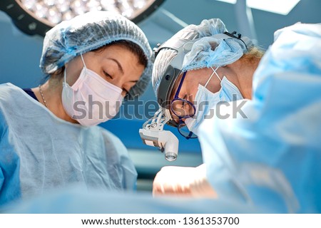 Team of surgeons makes an invasive operation. Portrait of surgeons close-up. Work with a coagulating instrument, vascular coagulation Royalty-Free Stock Photo #1361353700