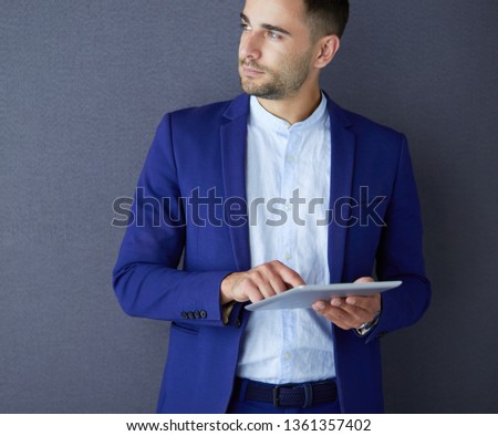Young businessman sitting isolated on grey background.