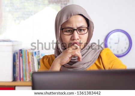 Portrait of young Asian muslim businesswoman seriously analyzing reading business chart report in office